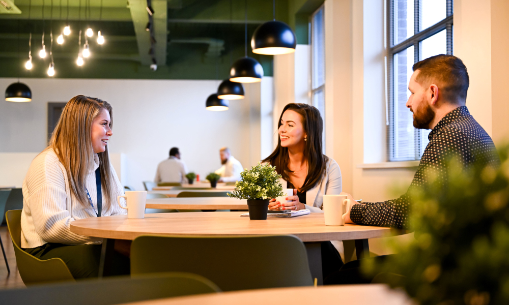 3 NIE Netorks smiling and chatting in the office canteen