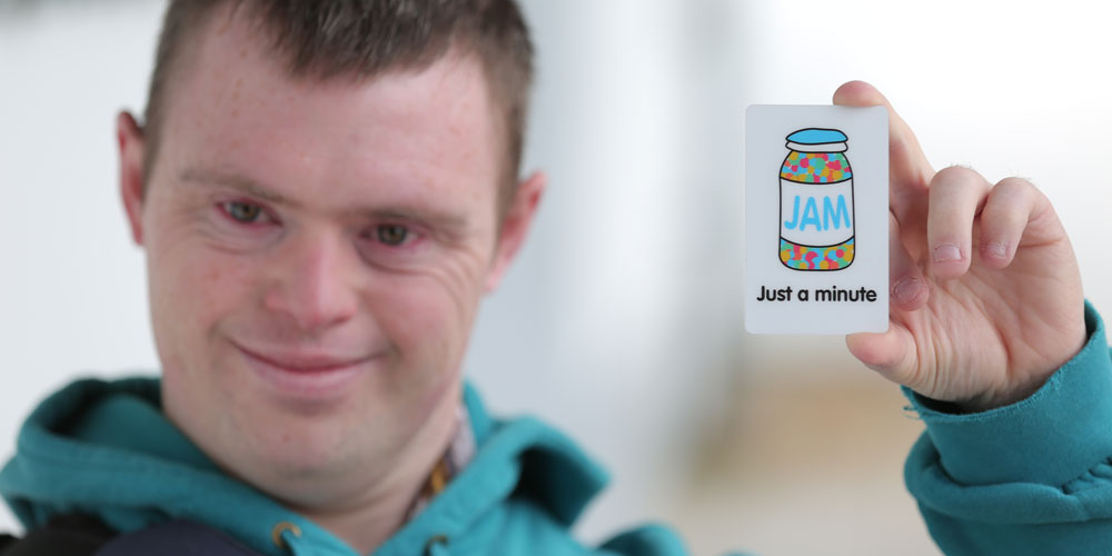 young man holding up a just a minute jam card