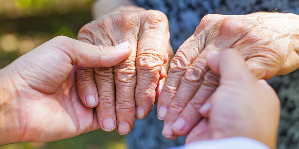 a younger person holding an elderly persons hands
