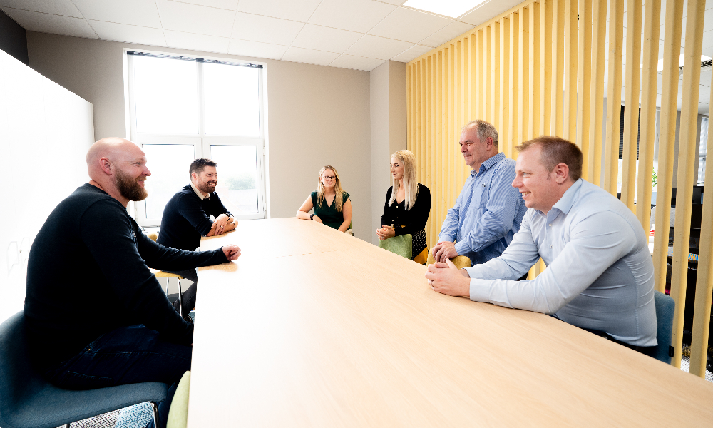 a group of NIE Networks employees in discussion sitting around an office table